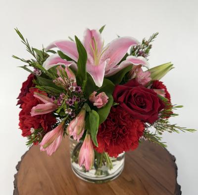 1 oriental pink lily, 4 red carnations, 3 red roses, pink wax, and pink alstroemerias in vase 