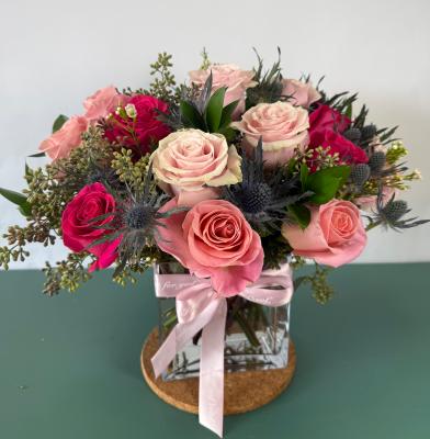 12 pink roses of varies hues, eryngo, seeded eucalyptus, Italian ruscus in a vase with a pink bow