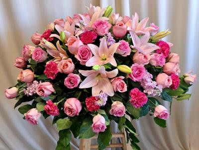 25 pink roses, 10 oriental lilies, pink carnations and stock filler casket spray arrangement 