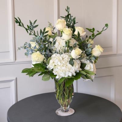 Upscale white rose arrangement in a footed vase.
